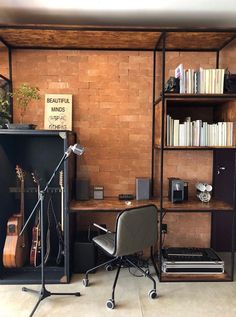 a room with a desk, chair and bookshelf filled with musical instruments in it