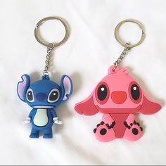 two keychains with cartoon characters on them sitting next to each other in front of a white sheet