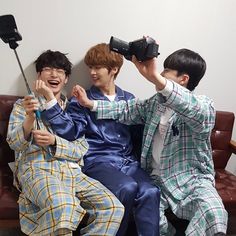 three boys sitting on a couch holding up cameras