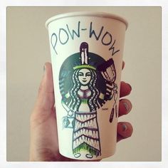 a person holding up a cup with the word pow wow on it