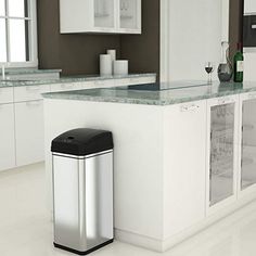 a modern kitchen with white cabinets and stainless steel trash can on the counter, along with a wine glass holder