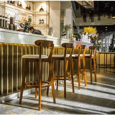 several wooden chairs are lined up at the bar