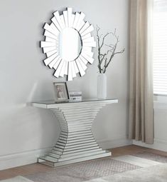 a white table with a mirror on top of it next to a vase filled with flowers