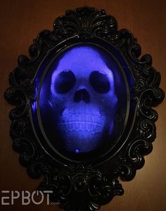 a blue skull in a black frame on a wooden surface with the reflection of it's face