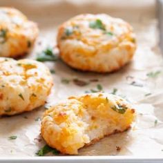 biscuits with cheese and parsley on top are sitting on a baking sheet, ready to be eaten