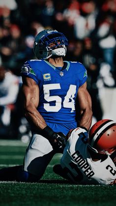 a football player laying on the ground next to another player with a helmet and ball