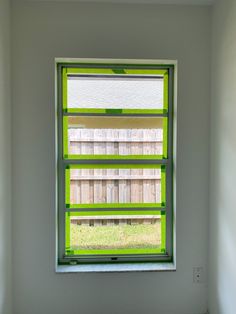 a window with green tape on it in the corner of a room that is painted white