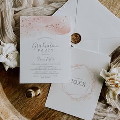 an open envelope with a wax stamp on it next to some wedding rings and flowers