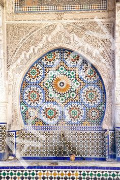 an intricately decorated wall in the middle of a building with blue and green tiles