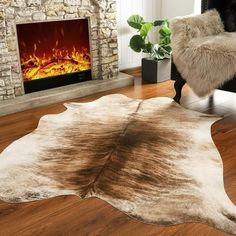 a living room with a fire place in the fireplace and a cow hide rug on the floor