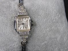 "For your consideration is this elegant vintage 1950's silver tone Woldman watch. It has a feminine decorative band, a beautiful face and decorative rhinestones accents. This watch has been professionally cleaned and repaired. It is a wind-up watch so I have the stem pulled out so it doesn't run down. It is in excellent condition. It band measures 5 1/2\" but it does stretch. The face measures 1/2\" across. Beautiful gift for any occasion.  I do not clean watches or jewelry. Thank you for visiti Elegant White Gold Diamond Watch With Bling, Elegant White Gold Embellished Diamond Watch, Vintage Evening Diamond Watch With Accents, Silver Art Deco Diamond Watch For Evening, Silver Art Deco Diamond Evening Watch, Timeless Formal Diamond Watch With Bling, Formal Watches With Rhinestones, Timeless Diamond Watch With Rhinestones For Formal Occasions, Elegant Silver Diamond Watch With Bling