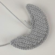 a crocheted mitt hanging from a string on a white surface with no background