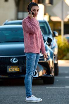 a woman standing in the street while talking on her cell phone