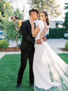 a bride and groom standing in the grass with their arms around each other as they kiss