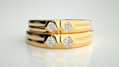 two gold wedding bands with diamonds on them, sitting next to each other in front of a white background