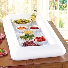 a large inflatable food tray filled with fruits and vegetables on top of a wooden table