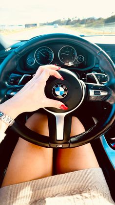 a woman is sitting in the driver's seat of a car with her hands on the steering wheel