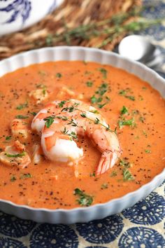 a bowl of soup with shrimp and garnish in it