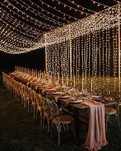 a long table set up with candles and place settings for an outdoor dinner party at night