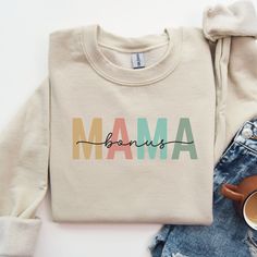 "Are you a stepmother or looking for the perfect gift for a stepmother in your life? Look no further than this cozy sweatshirt with the phrase \"Bonus Mama\" artfully displayed on the front. The word \"Mama\" in carefully curated muted colors is overlaid with the word \"bonus\" in a beautiful script font. She will be overjoyed to receive this thoughtful gift on her birthday, Mother's Day, or any time of the year! - 50% cotton/50% polyester blend - Loose unisex fit - Medium-heavy fabric - Sewn-in label HOW TO ORDER Please select your desired SIZE from the first drop-down menu and your desired COLOR from the second drop-down menu, then select ADD TO CART. Please refer to the size and color charts and send me a message with any questions prior to purchase.  CARE INSTRUCTIONS Machine wash cold Mother's Day Graphic Print Sweatshirt, Beautiful Script Fonts, Step Mom Gifts, Step Mother, One Drop, Mama Sweatshirt, Step Moms, Cozy Sweatshirts, Muted Colors