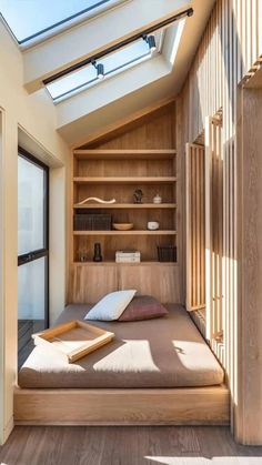 a bed sitting under a skylight in a bedroom next to a wooden shelf filled with books