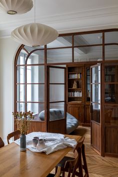 a dining room table and chairs in front of an arched glass door with shelves on either side