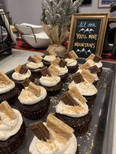 chocolate cupcakes topped with marshmallows and graham crackers on a baking sheet