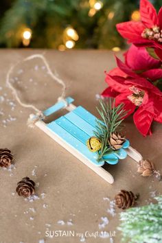 a wooden sled with pine cones on it next to a christmas tree and poinsettis