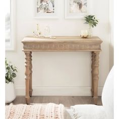 a wooden table with two pictures on the wall above it and a rug underneath it