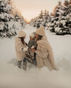 two women and a baby are sitting in the snow with their hands around each other