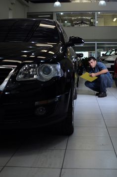 a man kneeling down next to a black car