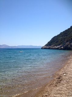 there is a boat that is out in the water at this beach and people are swimming