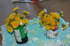 two vases filled with yellow flowers sitting on top of a blue cloth covered table