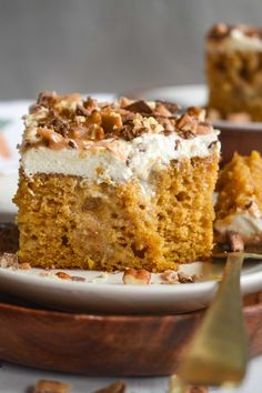 a piece of cake on a plate with pecans around it and another slice in the background