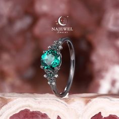 a ring with a green stone surrounded by diamonds