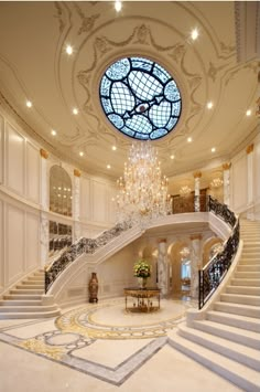 a large foyer with chandelier and marble steps leading up to the second floor