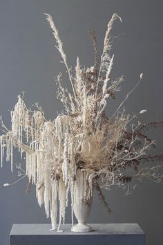 a white vase filled with lots of dried flowers