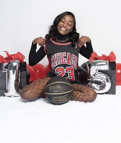 a woman sitting on the floor with her legs crossed and holding a basketball in front of her