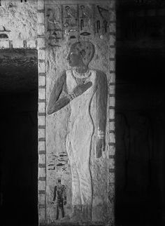 an ancient egyptian painting on the side of a wall in black and white with a man standing next to it