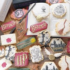 some harry potter themed cookies are on a table next to an open book and scissors