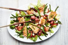 a white plate topped with meat and veggies on top of a wooden table