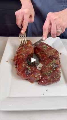 a person is cutting up some meat on a plate with a knife and fork in it