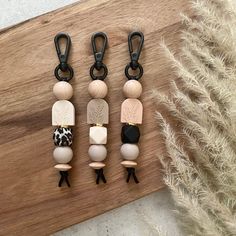 three wooden beads with black and white handles on a wood board next to some feathers