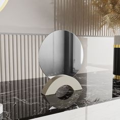 a black and white marble table with a mirror on it's side next to a vase