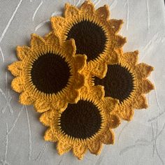 four crocheted sunflowers sitting on top of a white cloth covered table