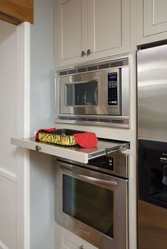 a microwave and oven in a kitchen with stainless steel appliances on the wall above them