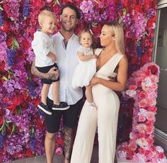 the couple and their two children are posing in front of a flower wall