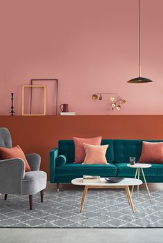 a living room with pink walls and blue couches in front of a coffee table