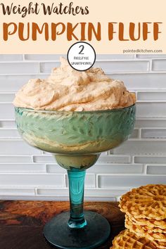 a glass bowl filled with pumpkin fluff on top of a table next to waffles