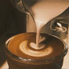 coffee being poured into a cup on top of a saucer